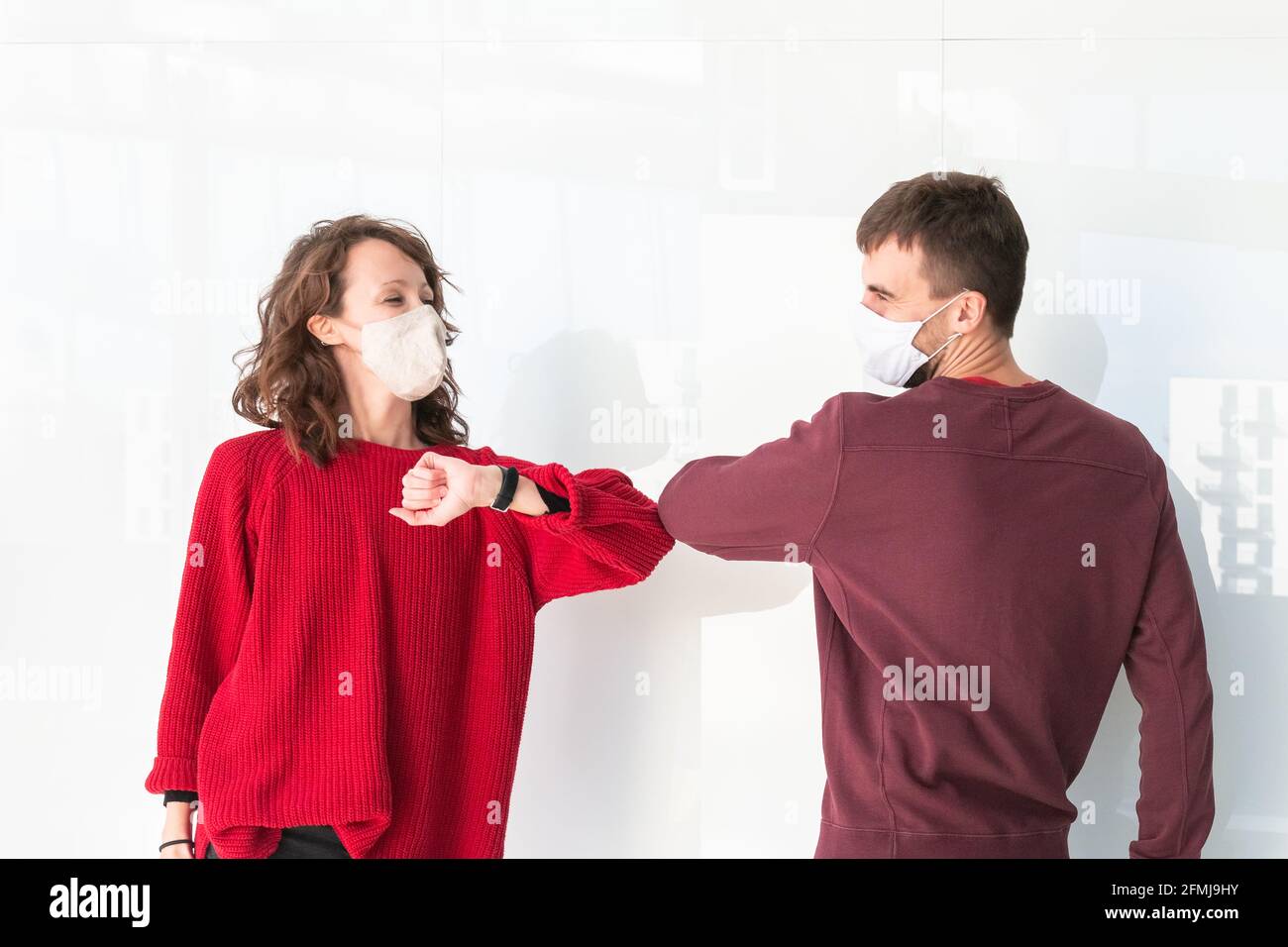 Two people greet elbow bump. Greeting with elbow bump in street. Colleagues are doing elbow bumps in office. New style of greeting during coronavirus. Stock Photo