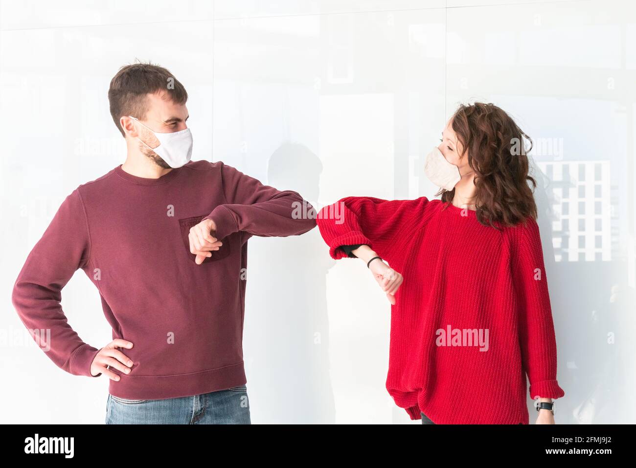 Greeting with elbow bump in street. Two people greet elbows bump. Colleagues are doing elbow bumps in office. New style of greeting during coronavirus Stock Photo