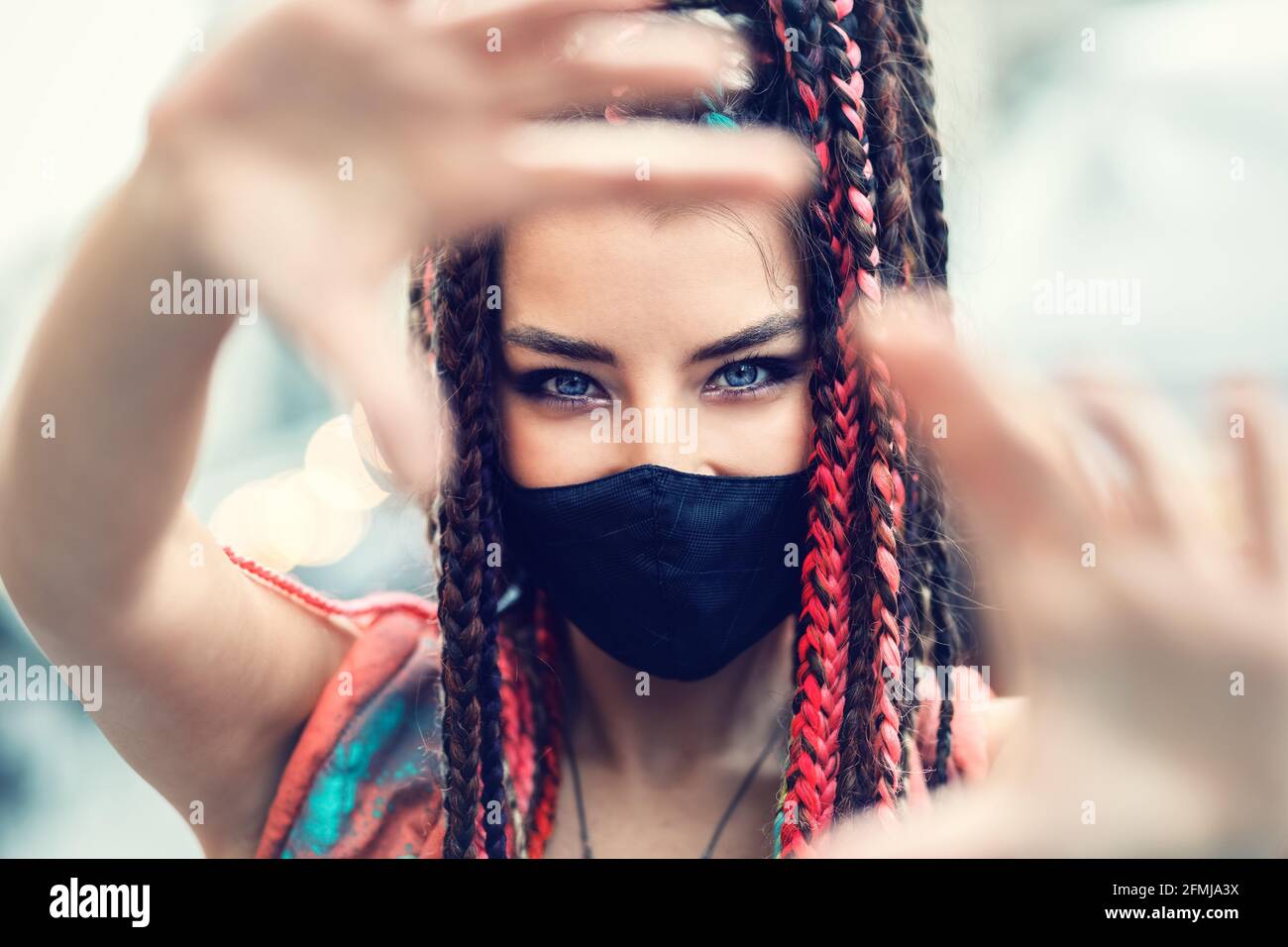 Playful cool rebel funky hipster young girl with face mask and crazy hair taking selfie on street Stock Photo