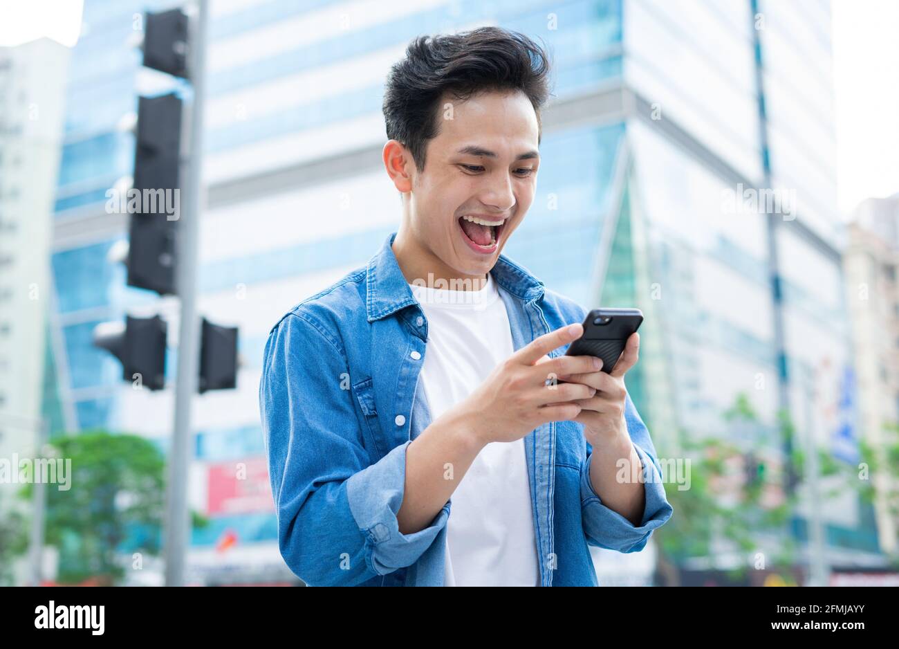 Young Asian man using smartphone while walking on the street Stock Photo