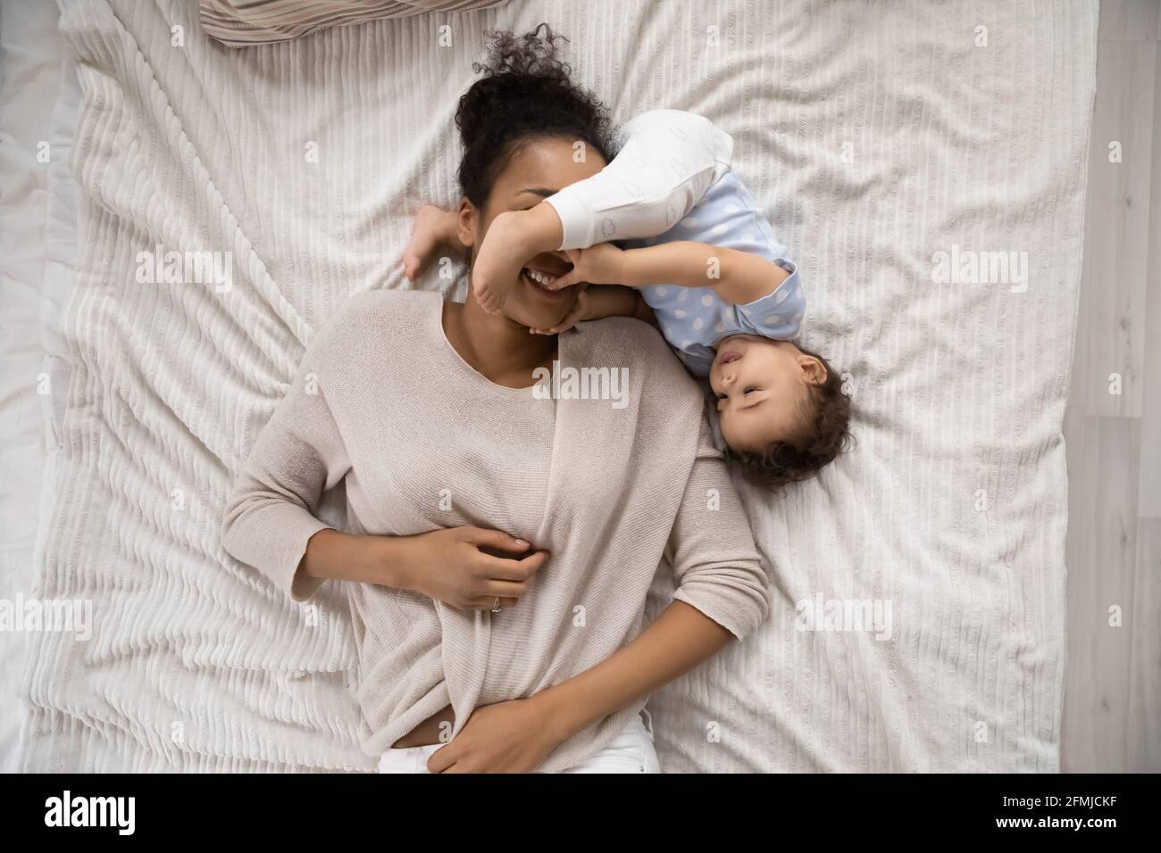 Smiling African American mom relax with little baby daughter Stock Photo