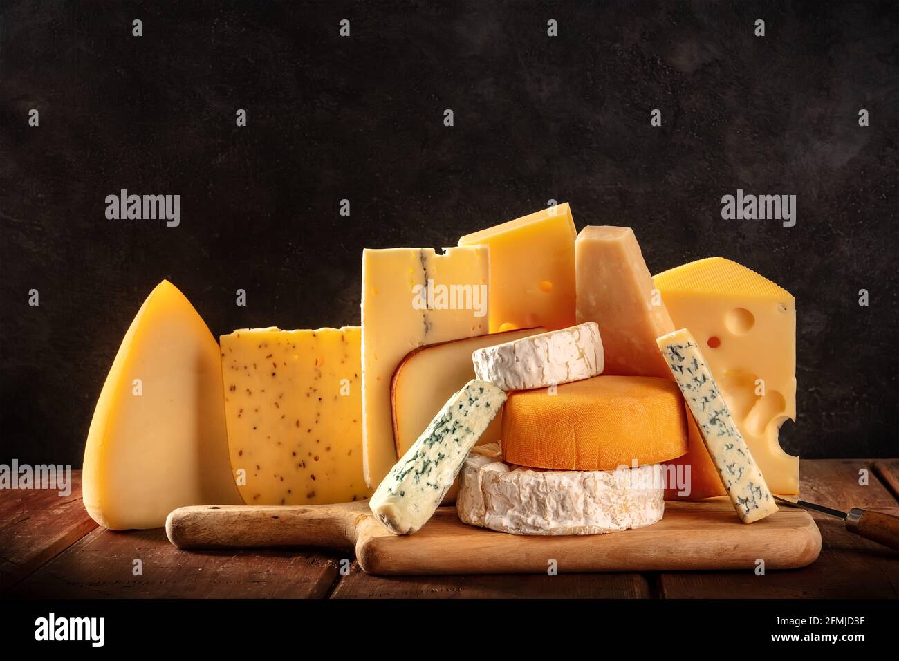 Cheese variety on dark rustic backgrounds. Soft and hard cheeses, side view with a place for text Stock Photo