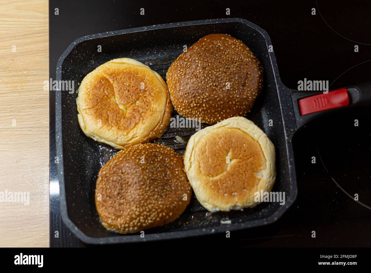 https://c8.alamy.com/comp/2FMJD8P/burger-bread-with-sesame-is-heating-on-a-grill-pan-process-of-cooking-self-made-burgers-at-home-2FMJD8P.jpg