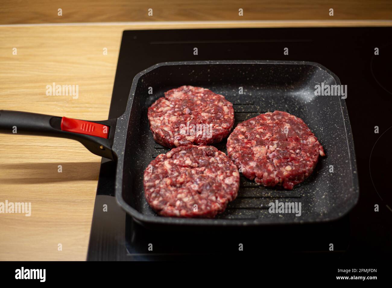 gebied Aanhoudend vonnis Burger raw minced beef meat cutlet on a grill pan. Process of cooking self  made burgers at home Stock Photo - Alamy