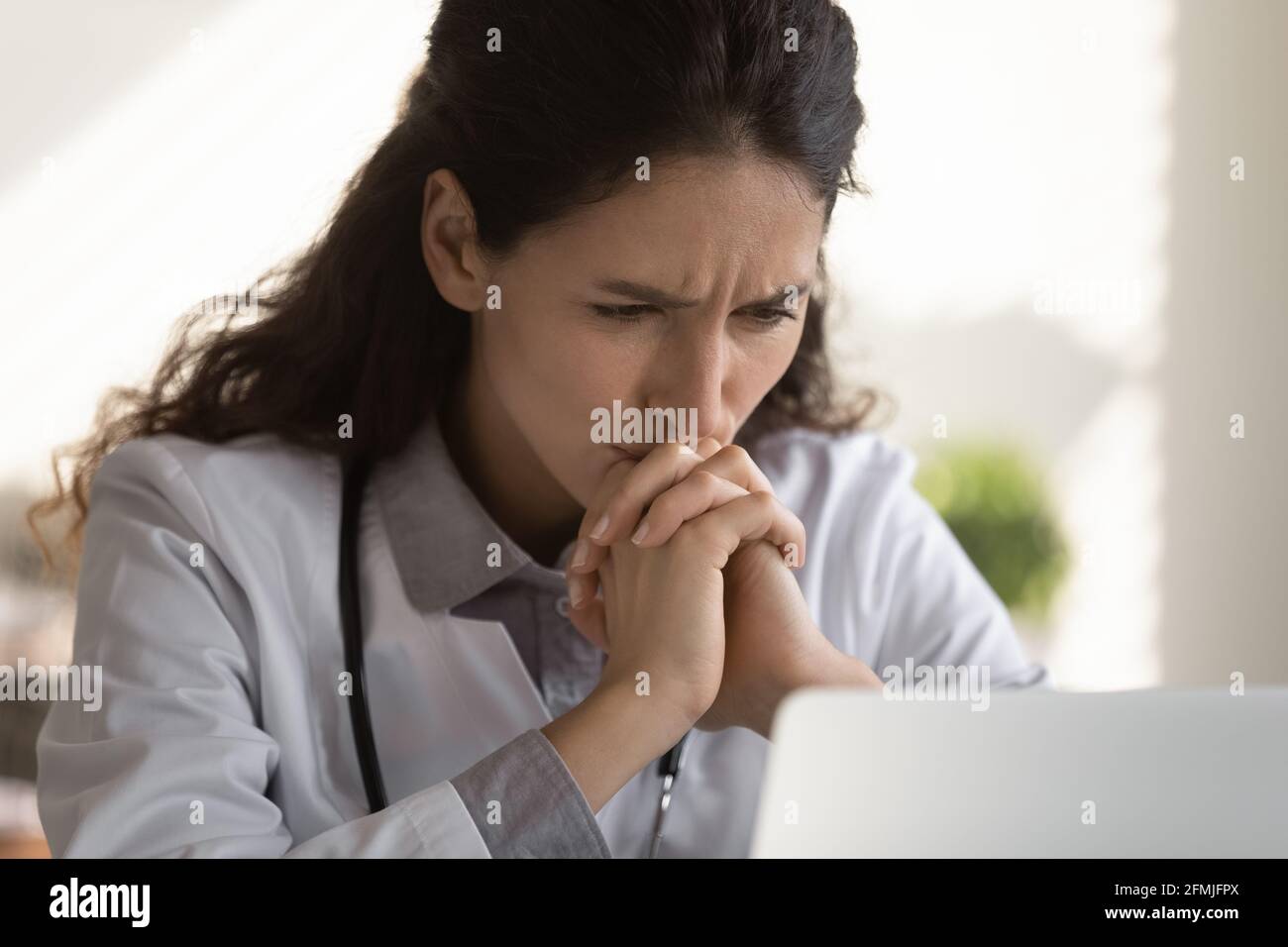 Thoughtful female doctor look at computer screen ponder on diagnosis Stock Photo