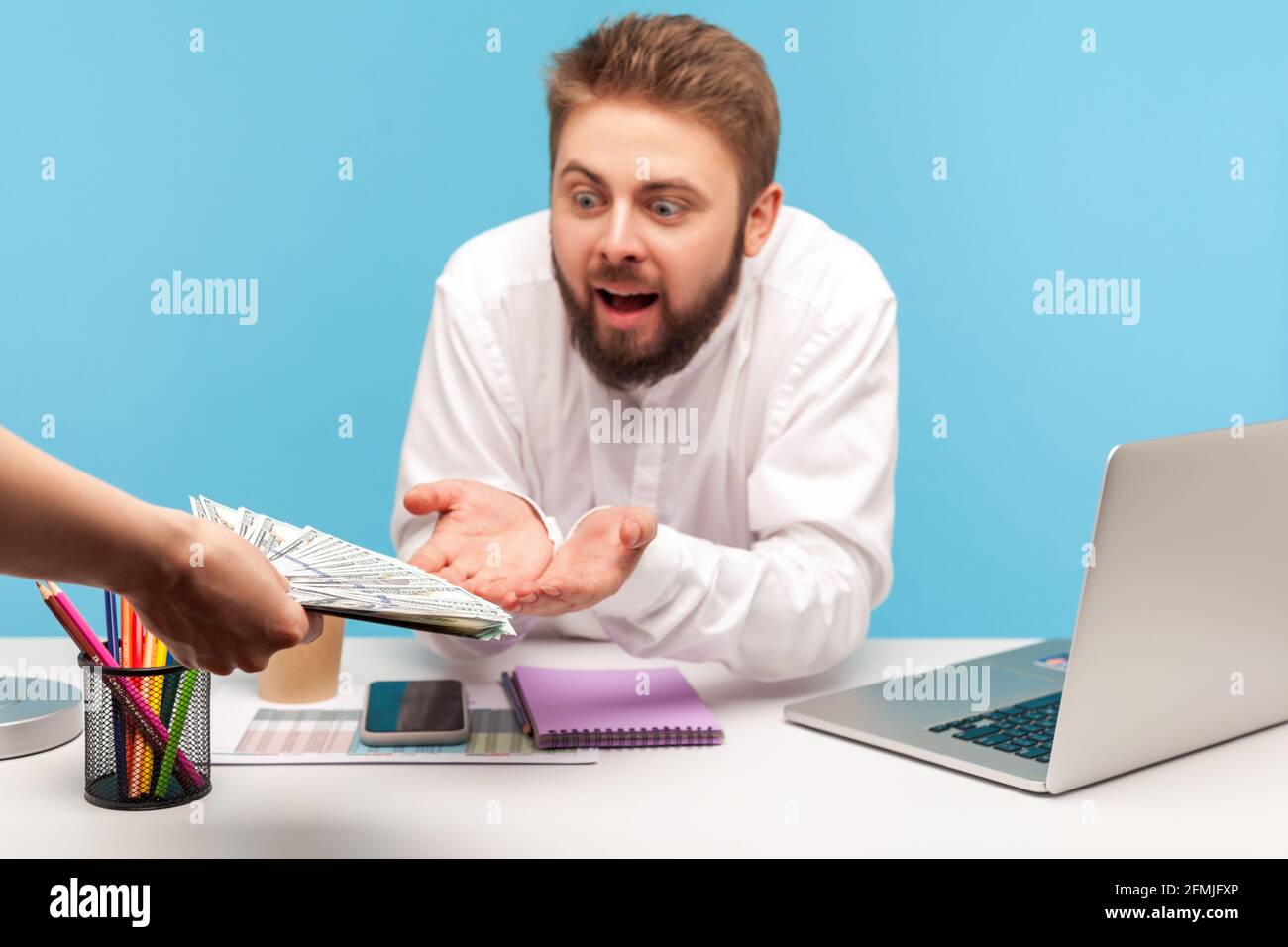 Shocked bearded man office worker looking at big sum of money in unknown person hands, receiving bribe sitting at workplace with laptop, tax avoidance Stock Photo