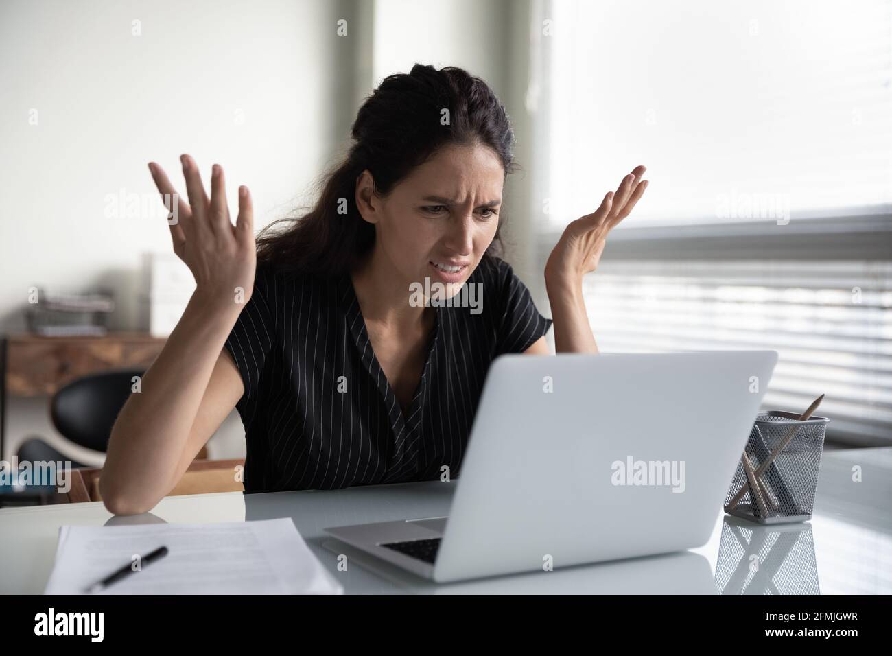 Mad young woman worker losing job result on broken pc Stock Photo