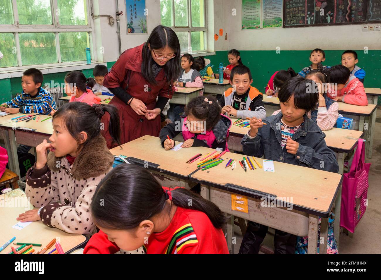 The teacher assists students at Xilain Primary school in Hebei with their classwork. Stock Photo