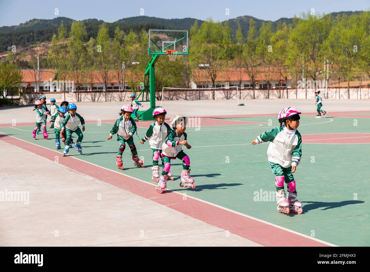 Students at BoAi school in Shanxi practice rollerblading around the basketball court. Stock Photo