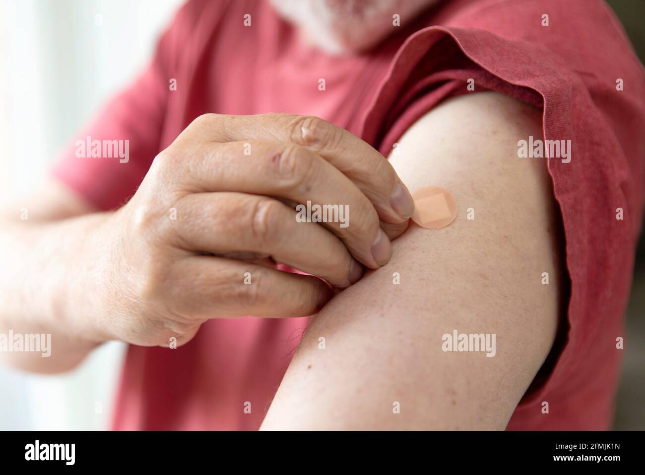 Caucasian man with a plaster on their arm after a vaccination injection Stock Photo