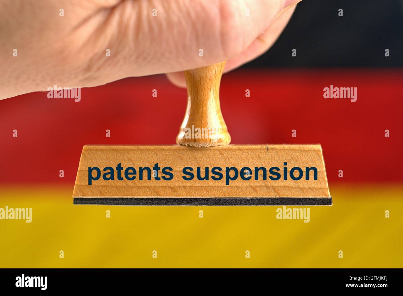 Deutschland. 07th May, 2021. A symbolic wooden stamp with the inscription 'patents suspension', held by a hand in a bleed in front of a blurred Germany flag in the background. Will there also be a patent release for the corona vaccines in Germany? Photo with composing [M]. | usage worldwide Credit: dpa/Alamy Live News Stock Photo