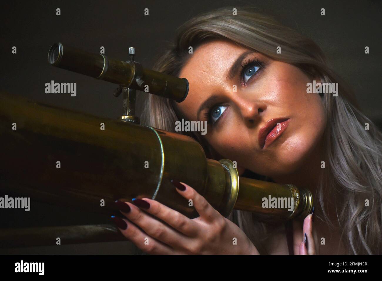 Beautiful blonde woman with old brass telescope, close up portrait Stock Photo