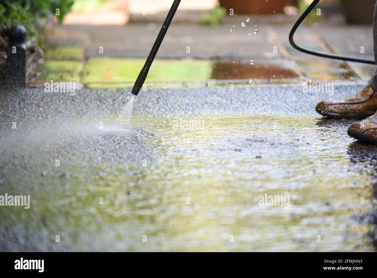 Cleaning patio paving with a high pressure washer the man is using the water to clean the garden path Stock Photo