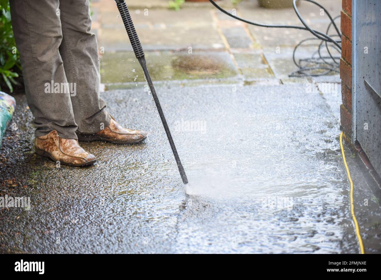 Cleaning patio paving with a high pressure washer the man is using the water to clean the garden