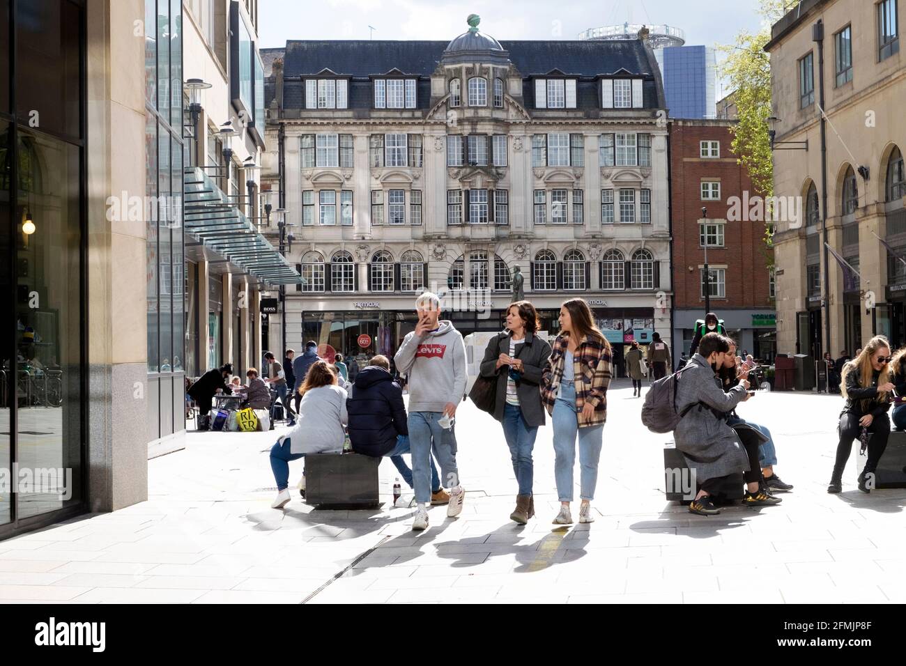 People shopping walking relaxing sitting on a sunny day in spring on pedestrianised street outside shops in Cardiff City Centre May 2021 KATHY DEWITT Stock Photo