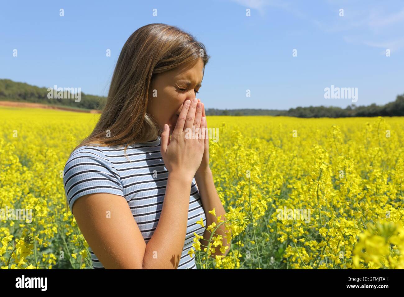 Allergic woman coughing covering mouth with her hands in a yellow field Stock Photo