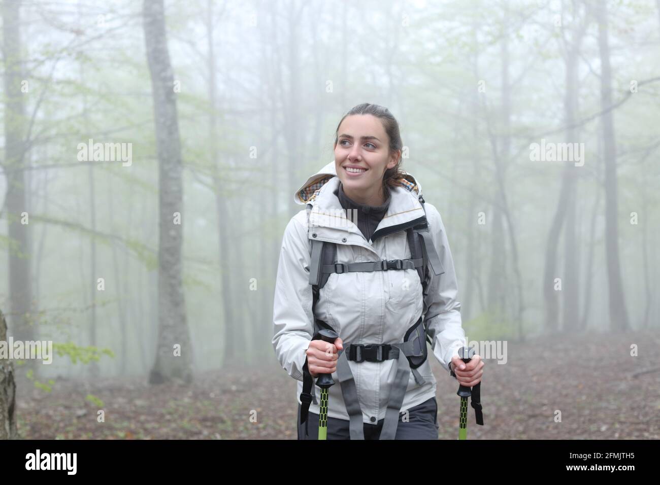 Front view portrait of a happy trekker walking in a foggy forest Stock Photo