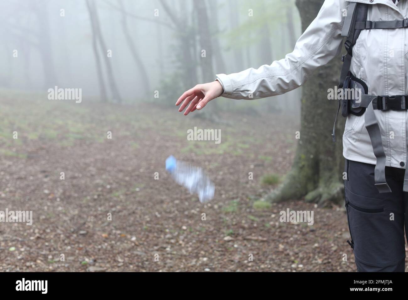 Close up of an uncivil trekker throwing garbage to the ground in nature Stock Photo