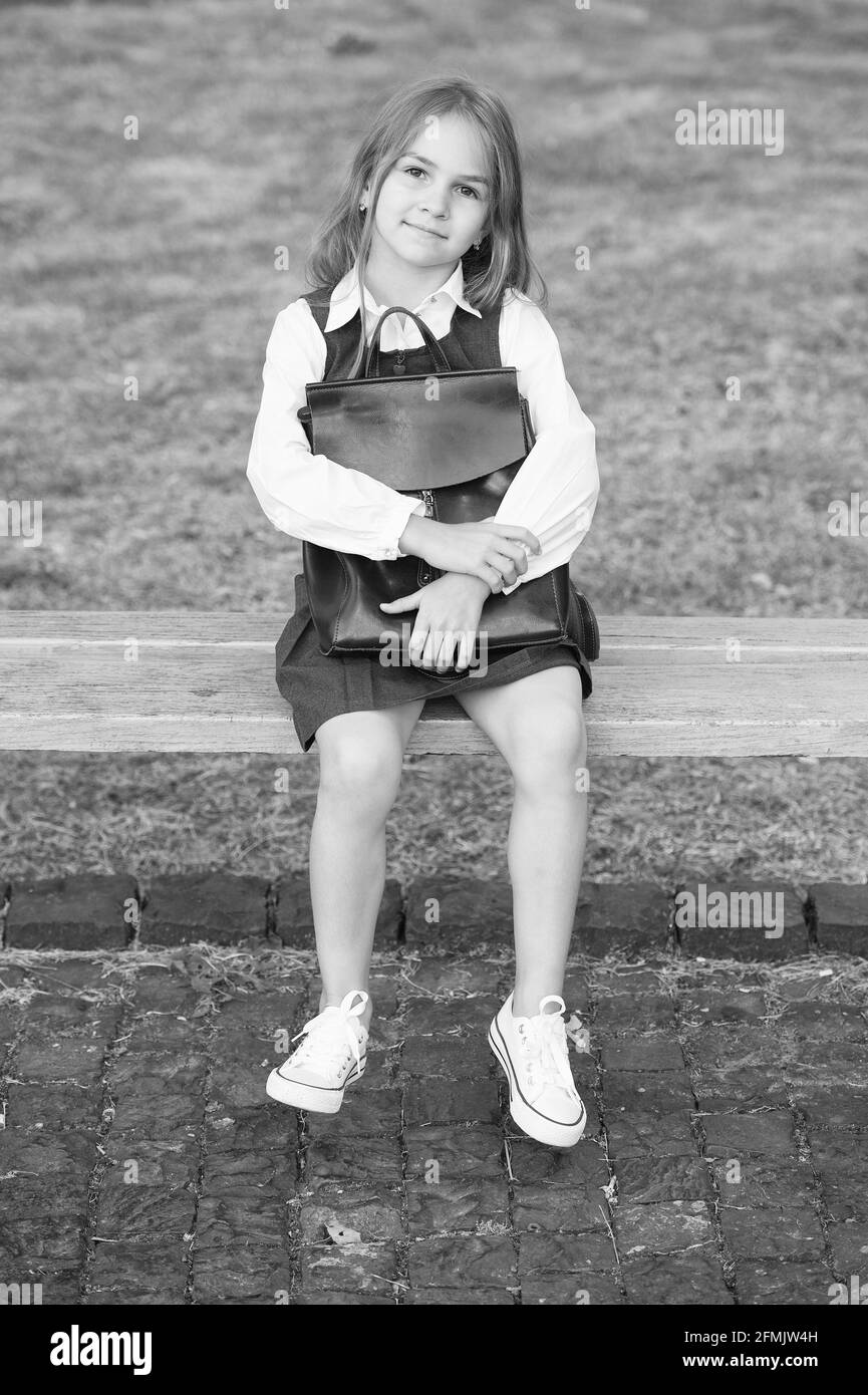 Educating tiny minds. Little kid in uniform sit on park bench. School ...