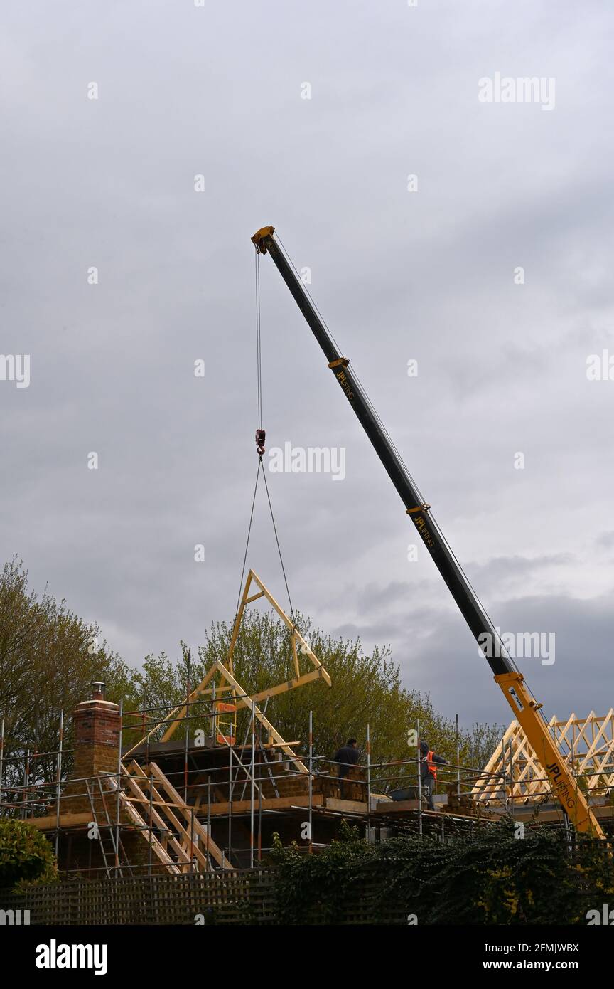 Crane in the course of lifting roof trusses into position on a building