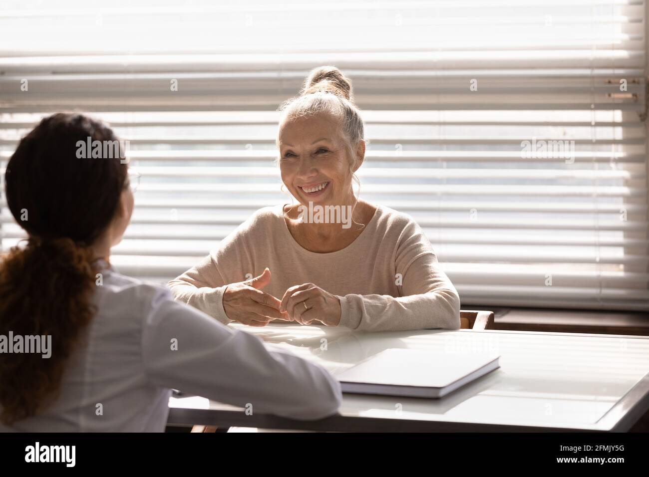 Smiling retired woman patient talking about health improvement with therapist Stock Photo