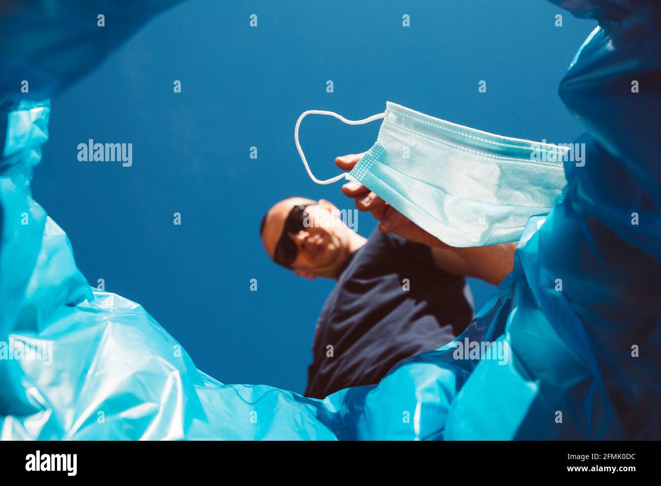 Man throwing a surgical mask in a garbage can. Concept for easing restrictions and ending the coronavirus pandemic. Stock Photo