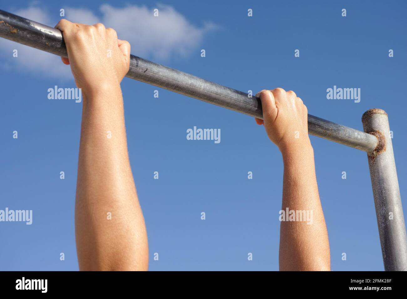 A person hanging on a horizontal bar against the sky. Close up. Stock Photo