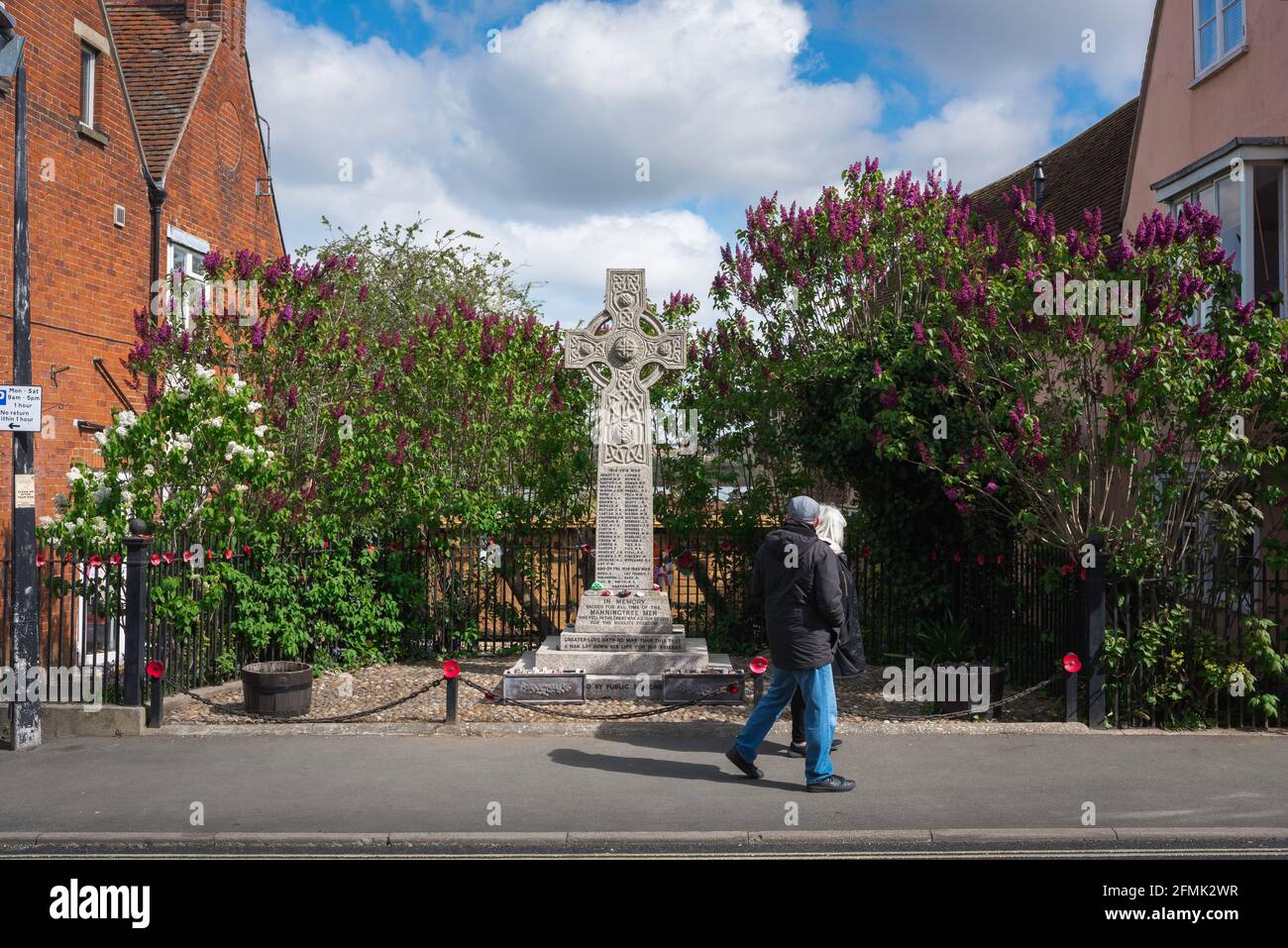 War memorial England, view of a middle aged couple walking past a war memorial sited in the high street of a small rural English town, Essex, UK. Stock Photo