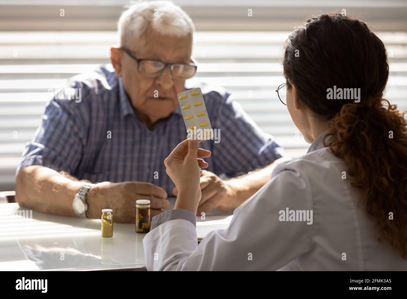 Female doctor pharmacist recommend effective pills to senior man oap Stock Photo