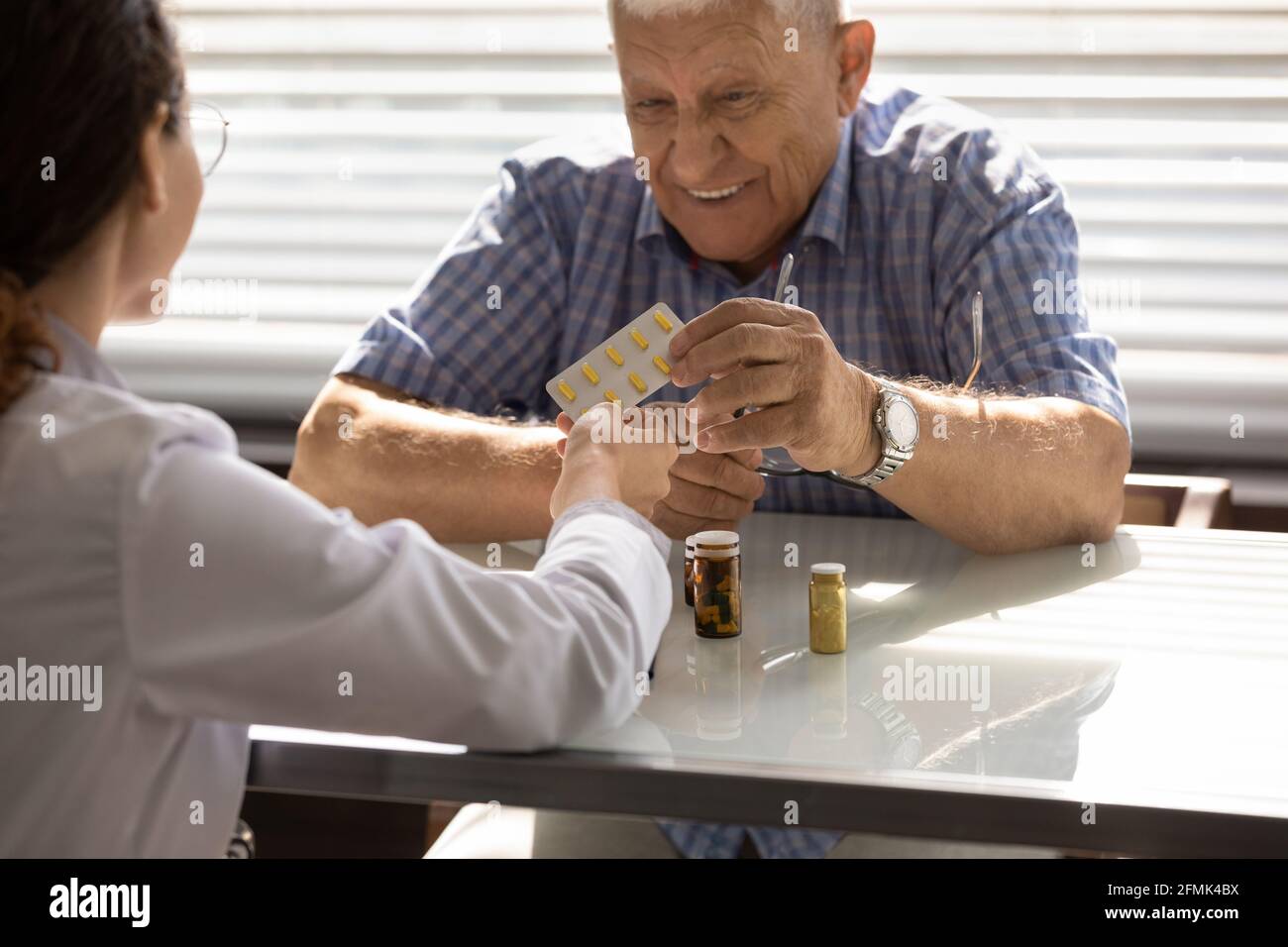 Therapist give medication to mature man under government sponsored program Stock Photo