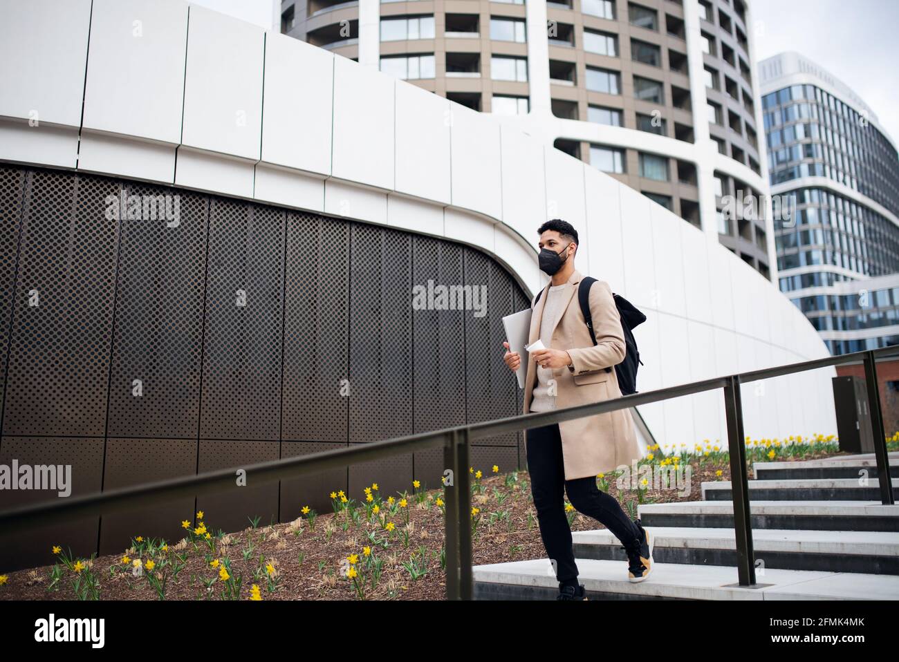 Happy man with laptop on the way to work outdoors in city, coronavirus concept. Stock Photo