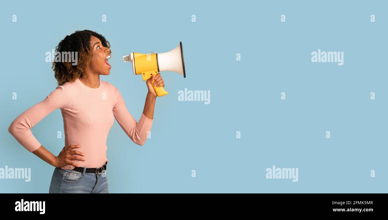 Amazing Offer. Young Black Woman Shouting With Megaphone, Making Announcement, African American Lady With Loudspeaker In Hands Sharing News, Standing Stock Photo