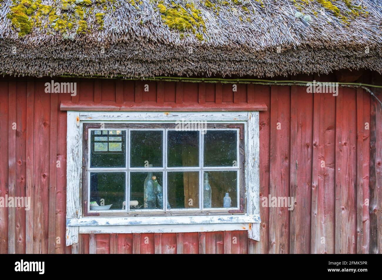 Old bottles in a window on red cottage Stock Photo