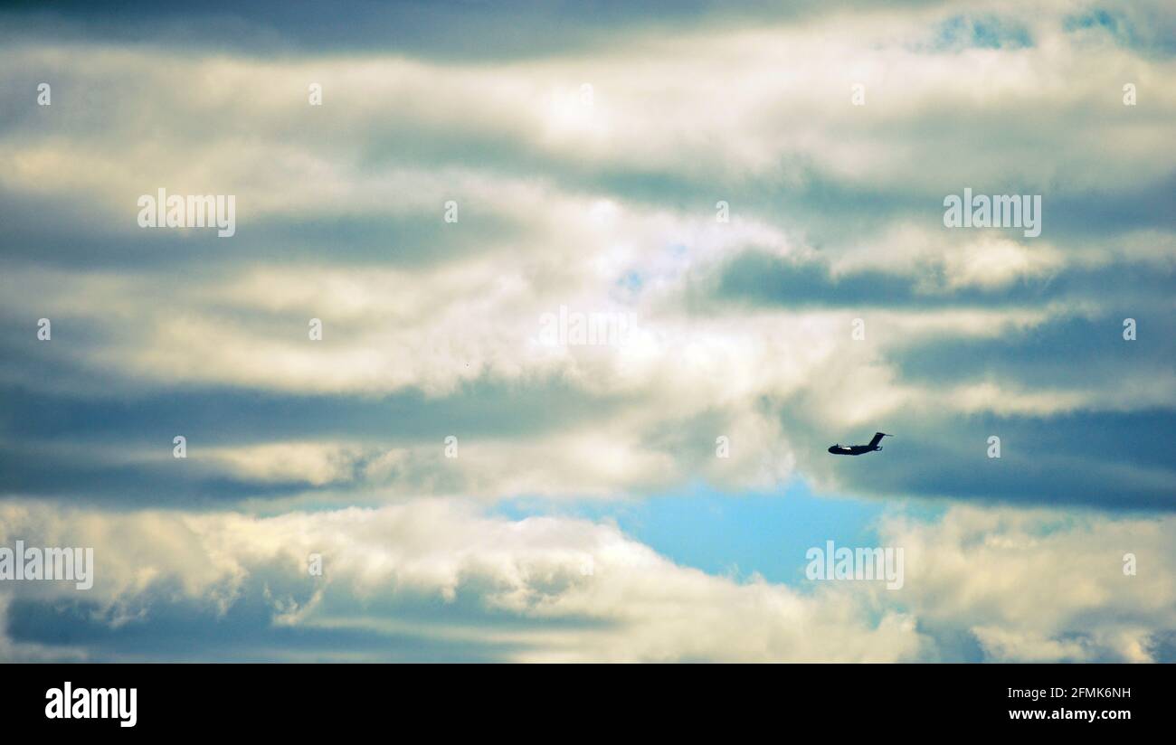 Airplane flying in dark cloudy sky Stock Photo