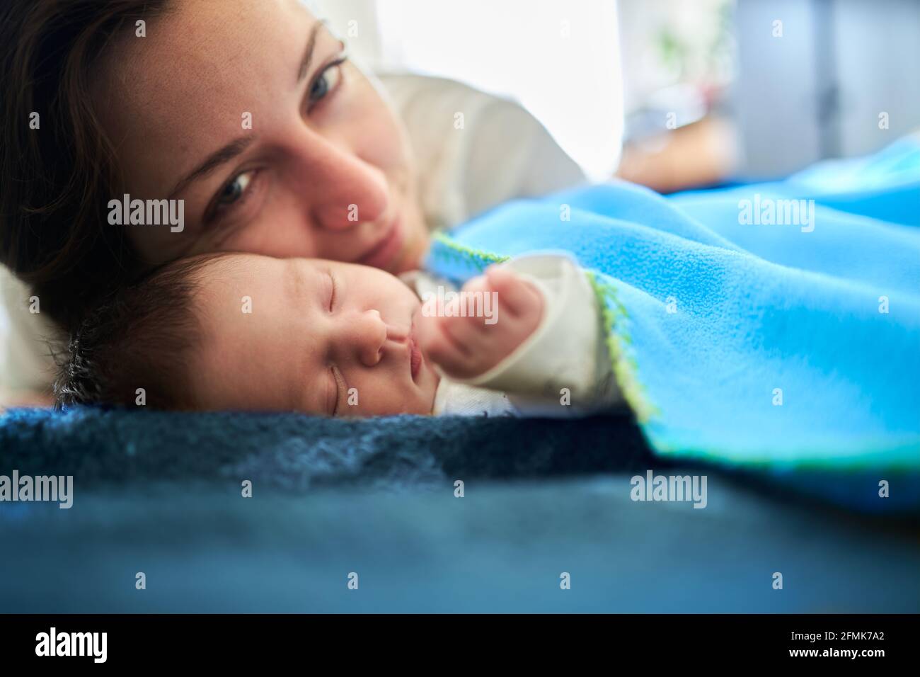 A mother expressing her love for her newborn child while the baby is peacefully sleeping Stock Photo