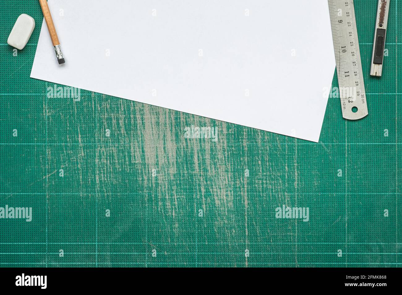 Old grunge green dirty cutting mat, with empty white paper A4 size