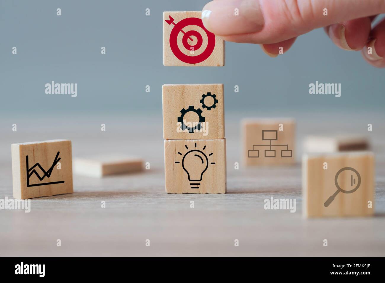 Business strategy, action plan, management concept. Businesswoman hand putting wood cube block with target icon on top of other cubes Stock Photo