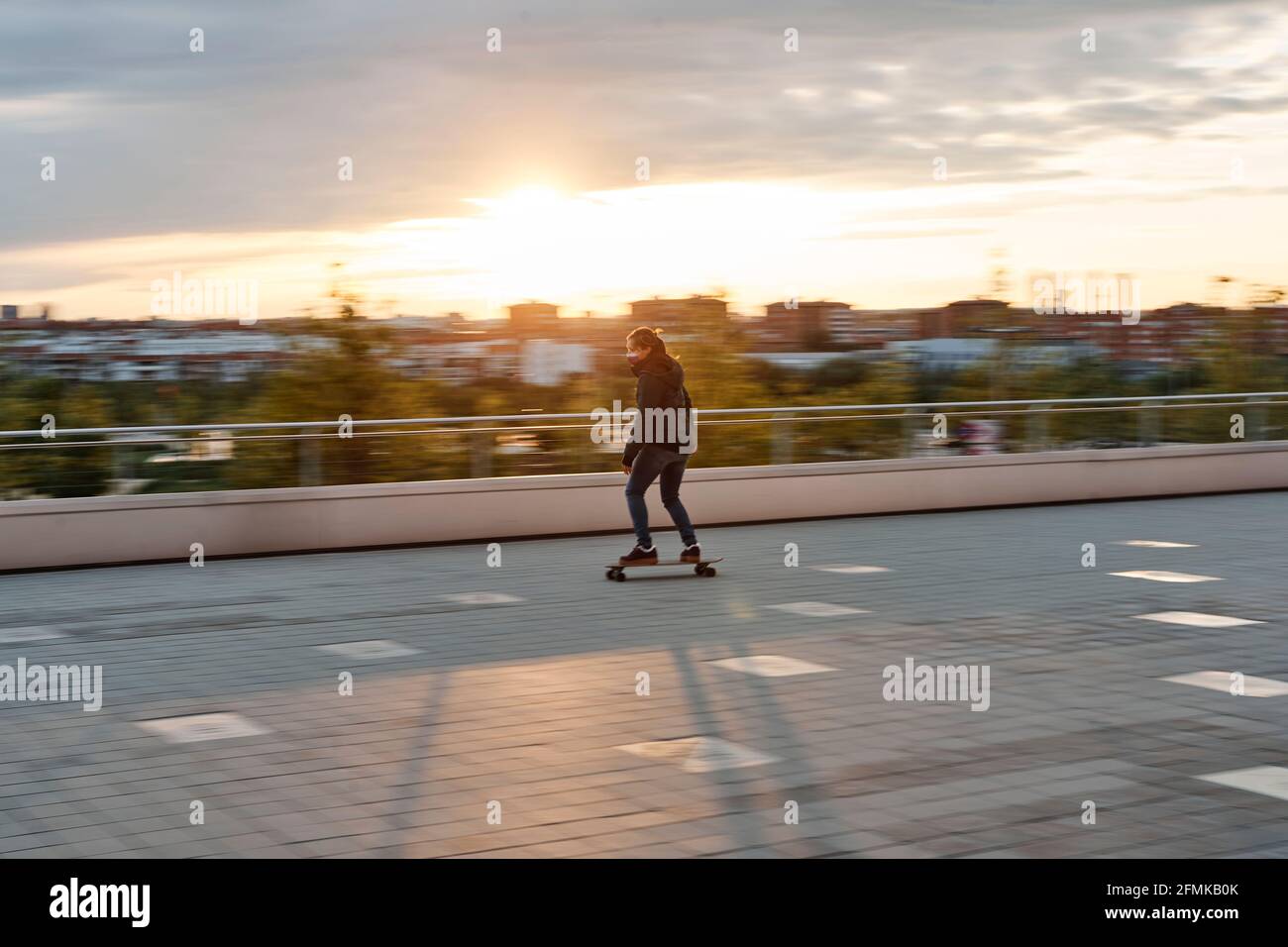 Young girl riding a skateboard in the city. Picture taken by means of a photographic panning, with blurred background. Concept of sustainable transpor Stock Photo