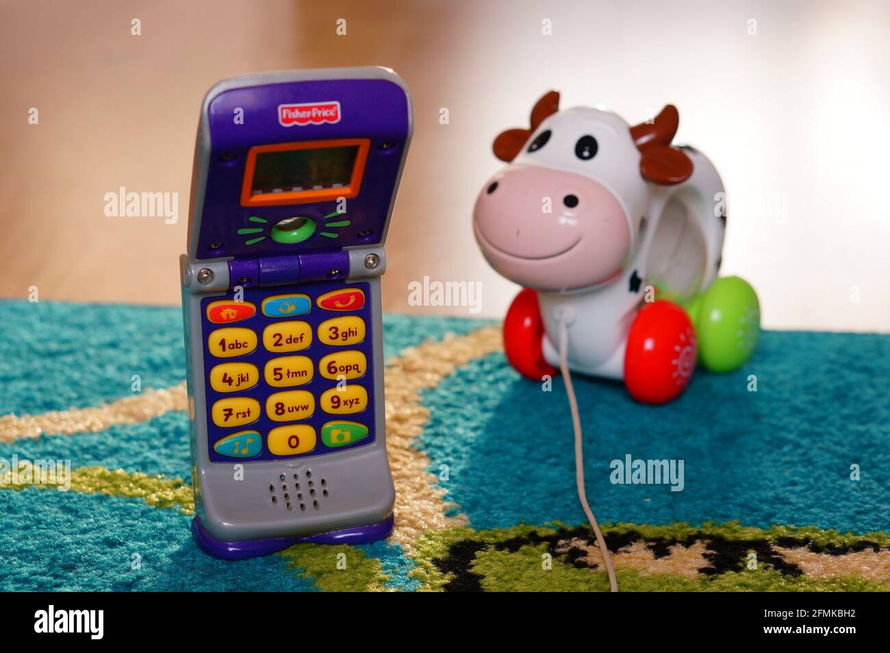 POZNAN, POLAND - Aug 20, 2015: Fisher Price plastic toy phone and toy cow in background Stock Photo