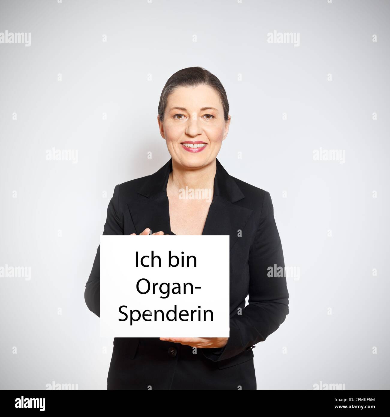 Organ donation concept: mature woman holding up a white sign with the text I am an organ donor in german. Stock Photo