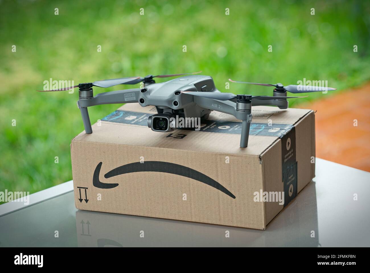 Selective focus on drone delivering parcel with amazon logo on cardboard. Milan, Italy - May 2021 Stock Photo