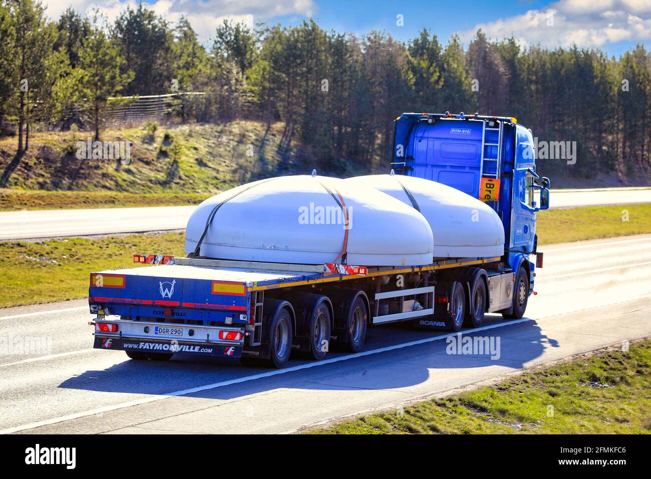 Blue Scania semi trailer truck transporting circular steel objects as oversize load, rear view. Salo, Finland. April 30, 2021. Stock Photo