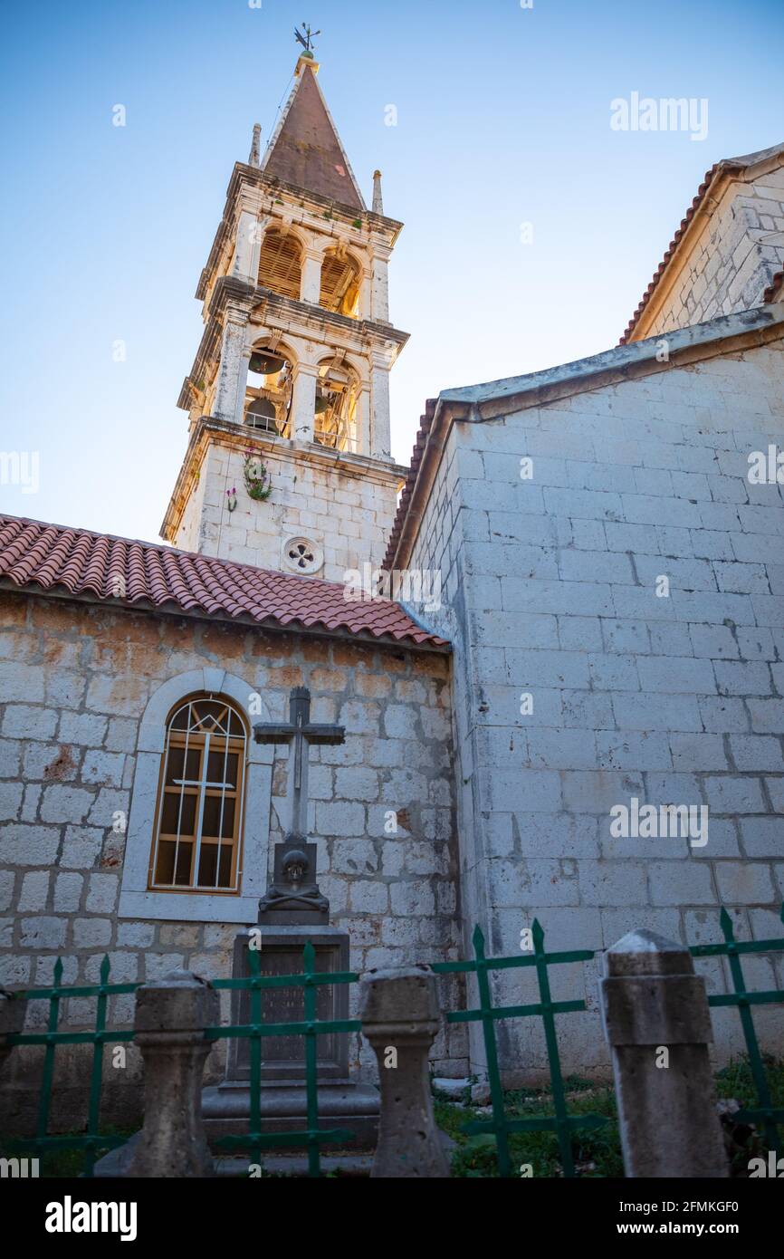 Bell tower of the Church of Our Lady of the Annunciation at the end of a narrow street in the town of Milna on Brac island in Dalmatia, Croatia Stock Photo