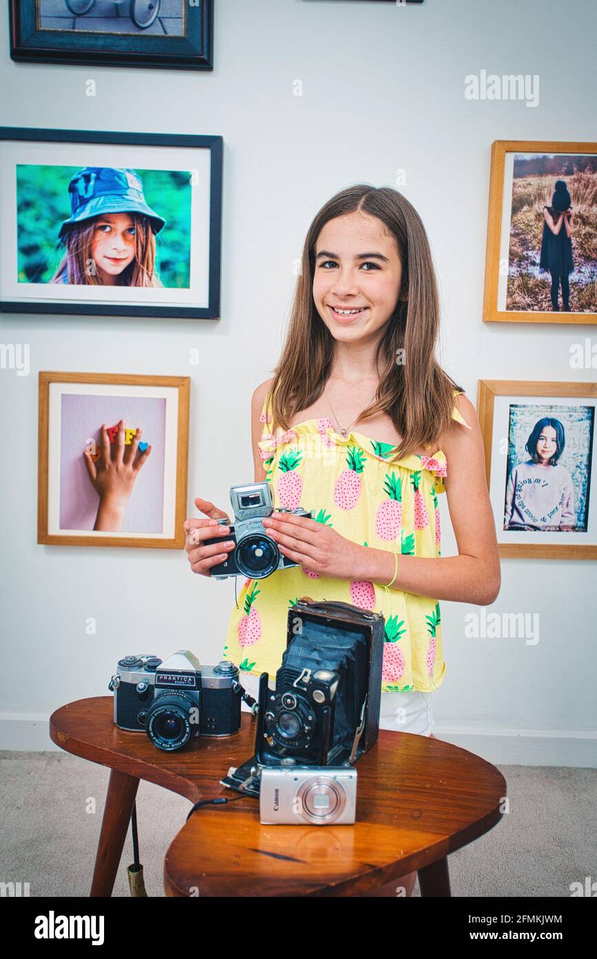 young girl holding vintage camera at home. Stock Photo