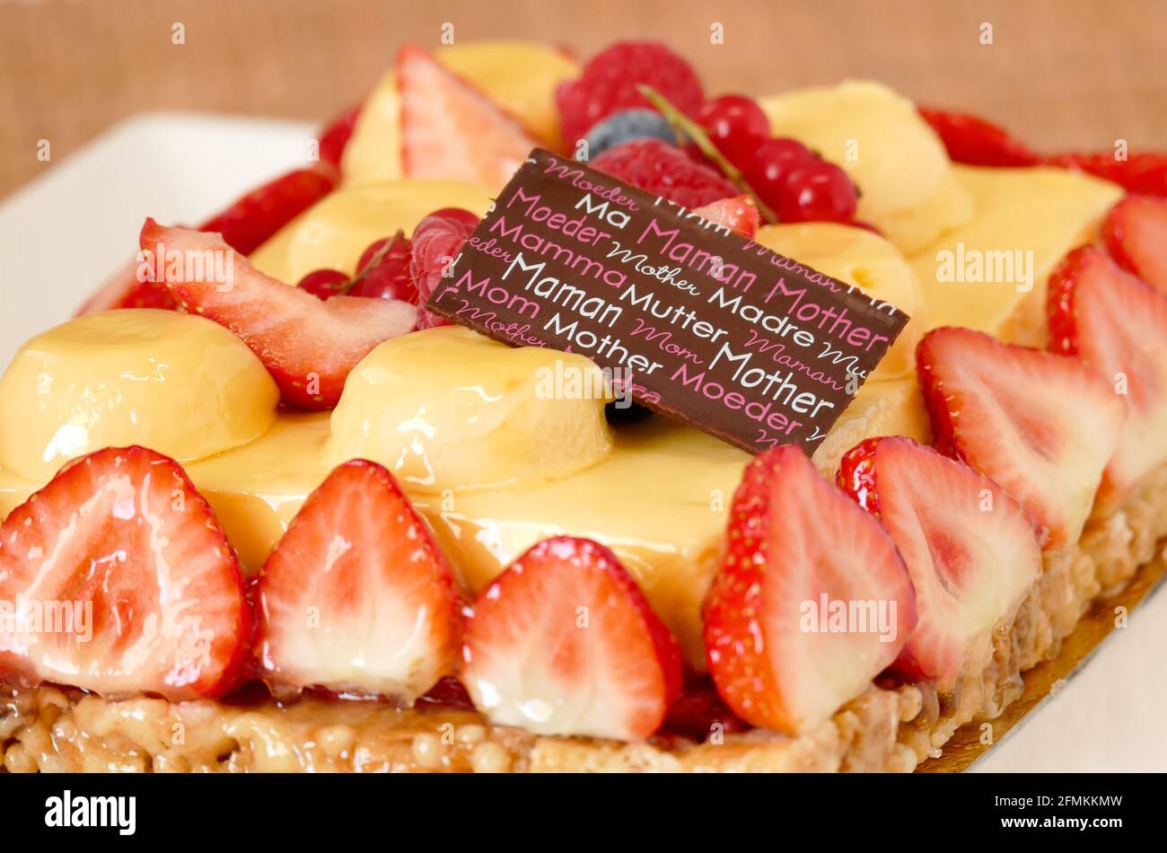 Motherday fruit tart closeup, yellow cream with passion fruit flavor and red berries coulis and strawberries on caramel crust Stock Photo