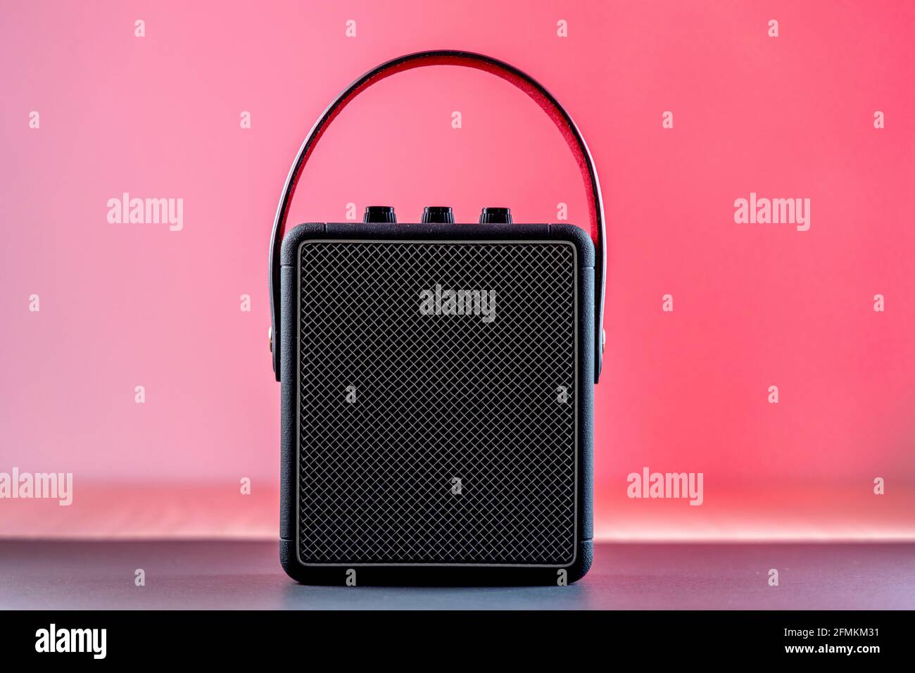 Black modern bluetooth loudspeaker on a pinkish background Stock Photo