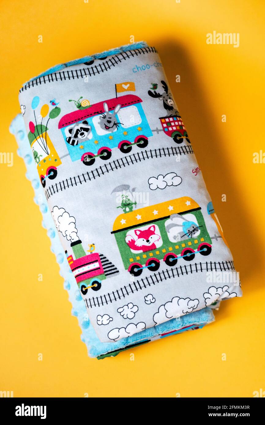 Sweet and cozy baby blanket with train pattern isolated on yellow background Stock Photo