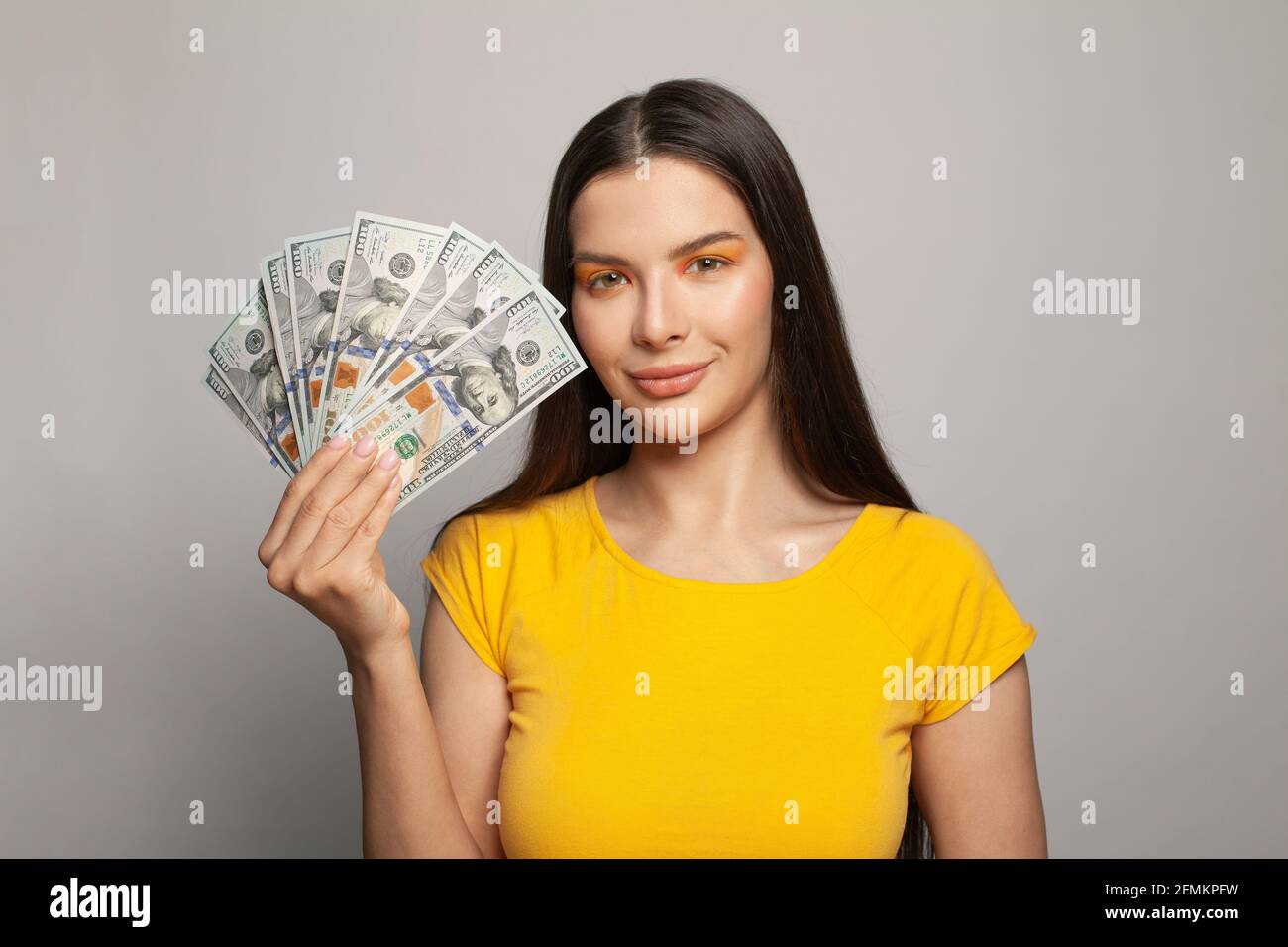 Happy brunette woman holding US dollars cash money on white background ...
