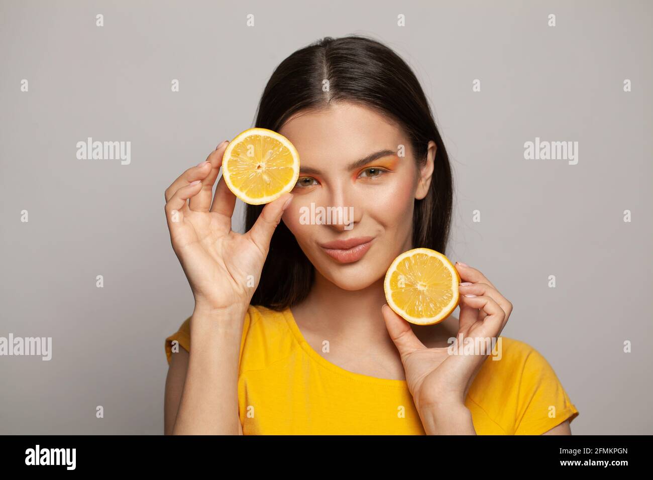 Portrait of attractive young healthy model woman with clear skin and  straight brown hair holding lemon fruits on white background. Diet,  skincare and Stock Photo - Alamy