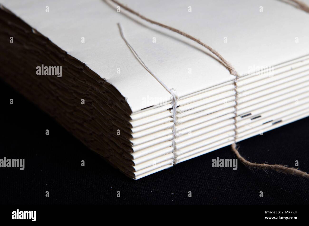 The process of book binding; close up of a raw book after sewing on cords. Black background